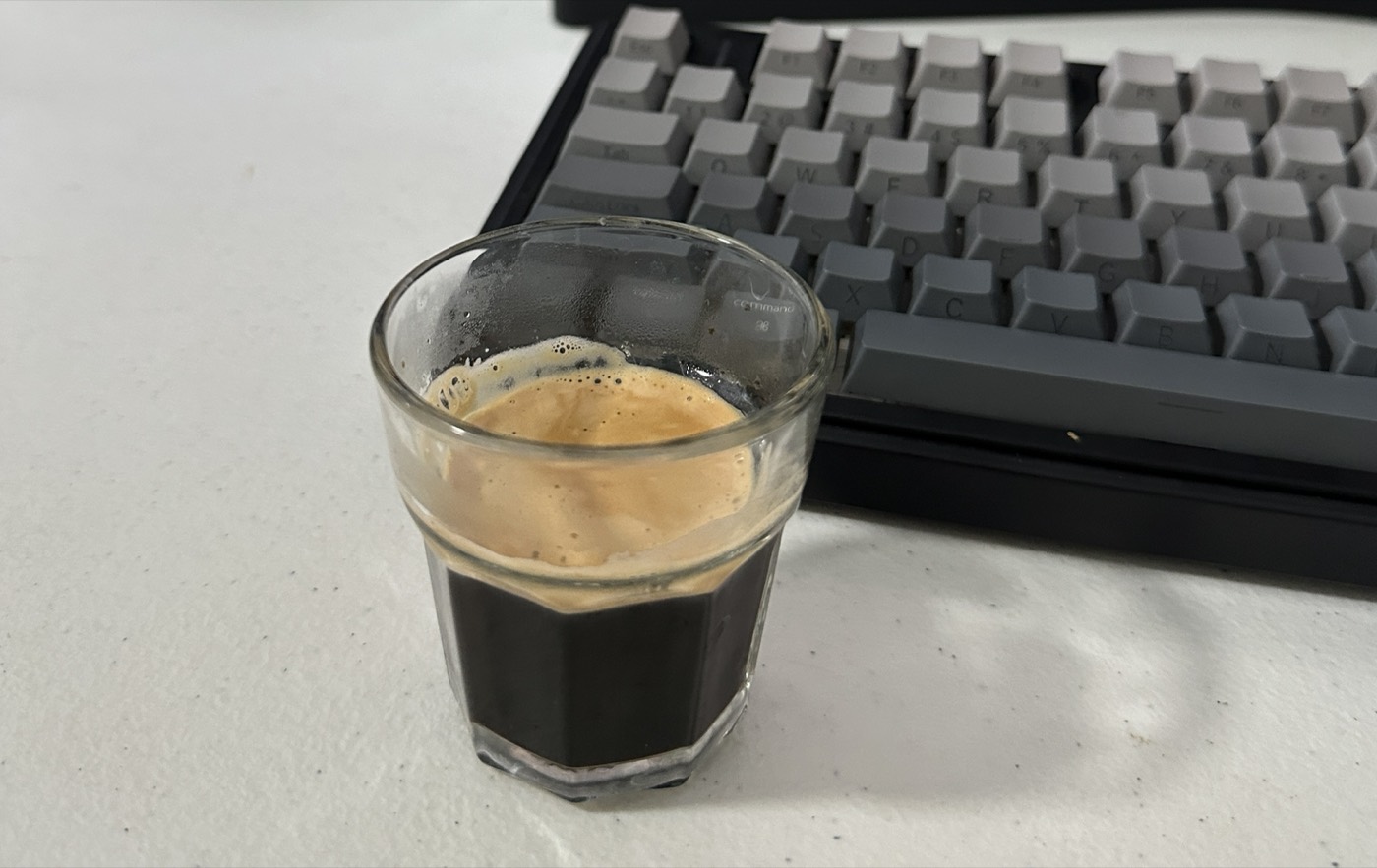 Espresso shot next to a mechanical keyboard on John Arce's desk