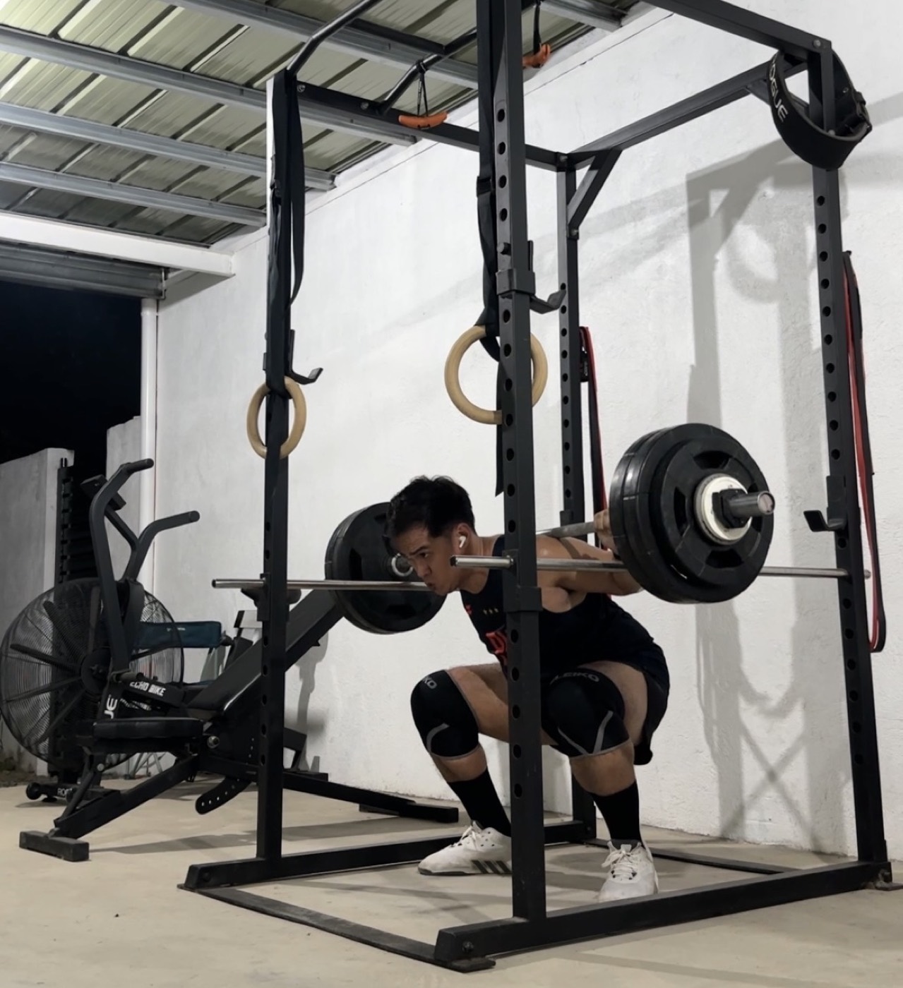 John Arce doing a heavy barbell squat in his home gym